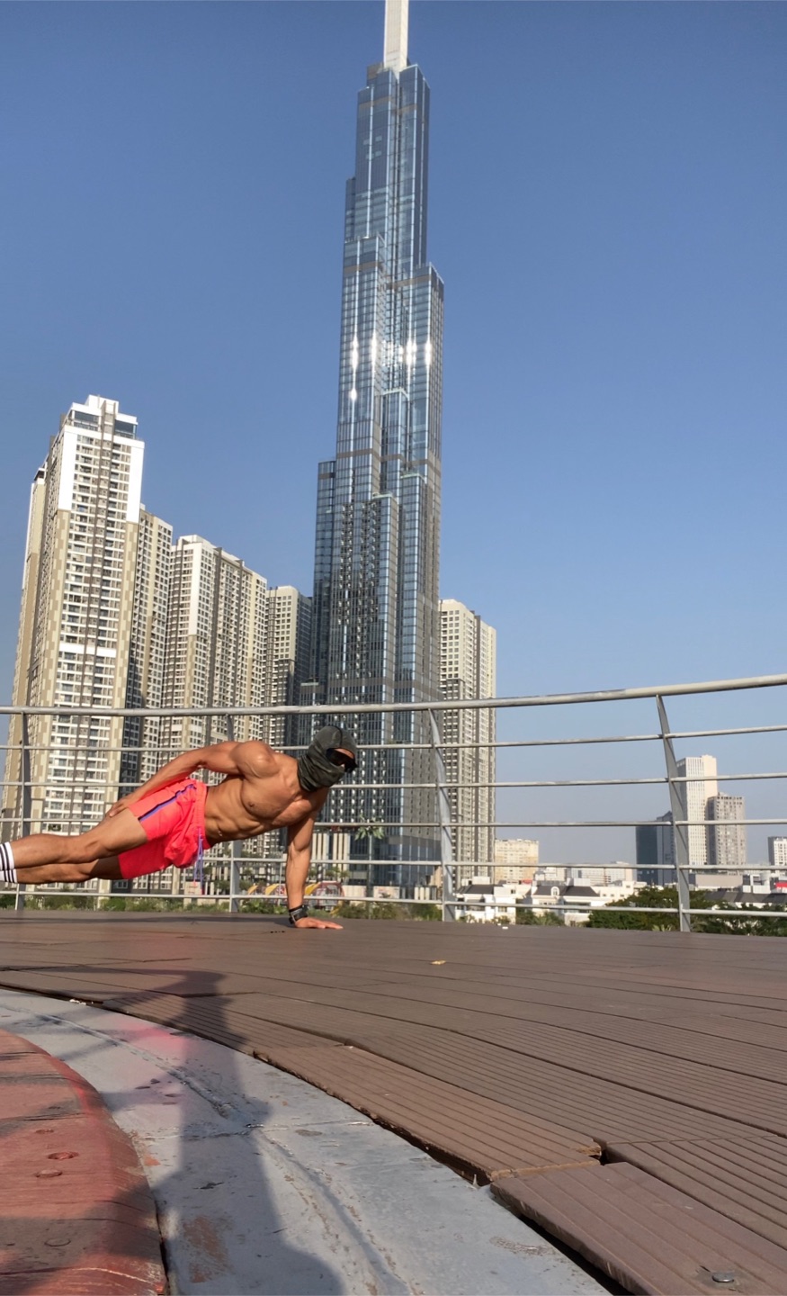 OYOTTA holding a side plank on an outdoor deck with a city skyline